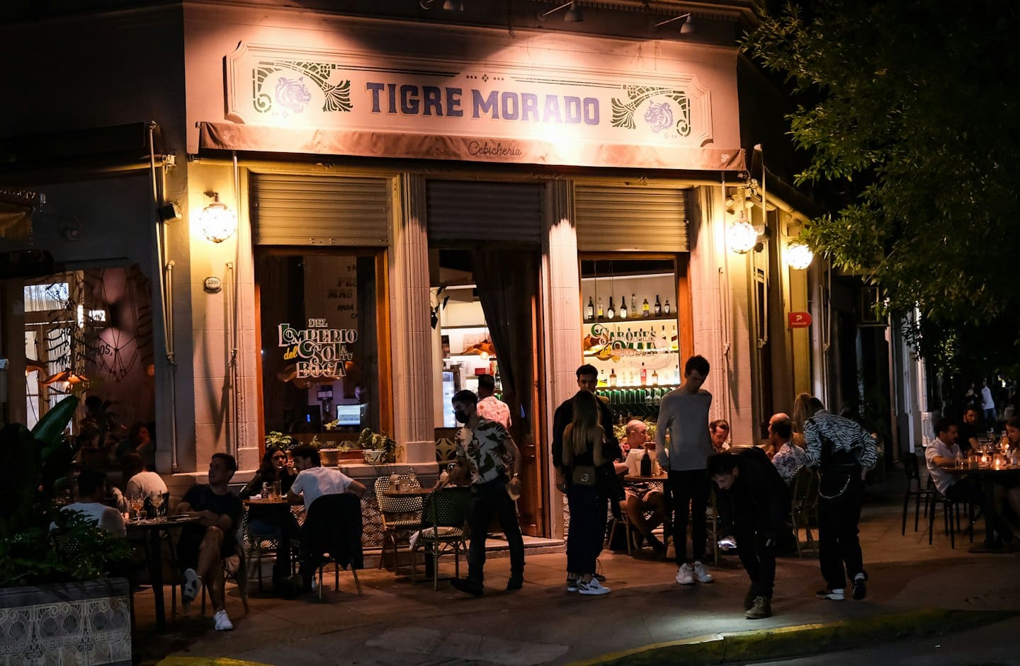 Persone che cenano e socializzano in un ristorante all'aperto di notte.